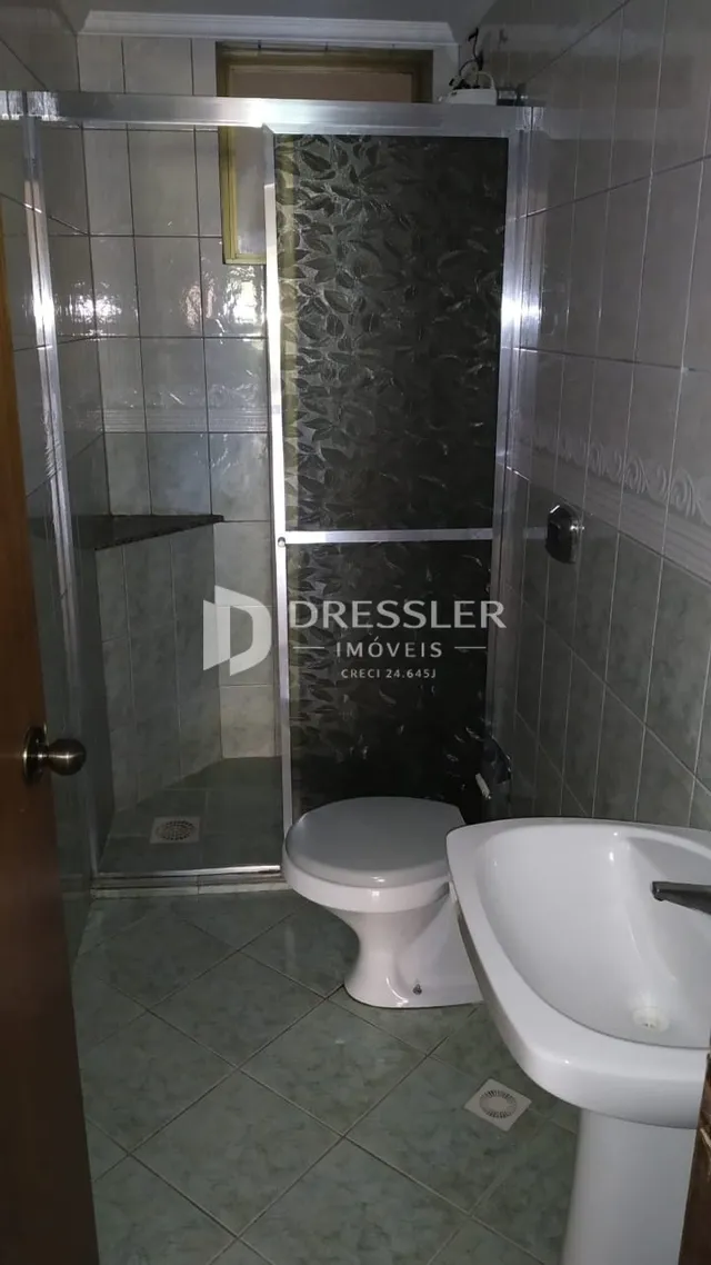 Foto de um banheiro com revestimento cerâmico e box de vidro.