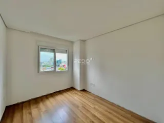 Sala de estar com piso de madeira clara e janela com vista para a cidade.