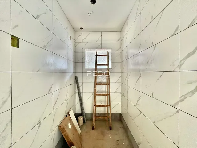 Corredor interno com paredes de azulejo branco e materiais de construção visíveis.