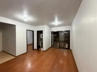 Hall de entrada com piso de madeira e portas internas em uma residência.