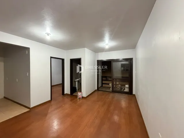 Hall de entrada com piso de madeira e portas internas em uma residência.