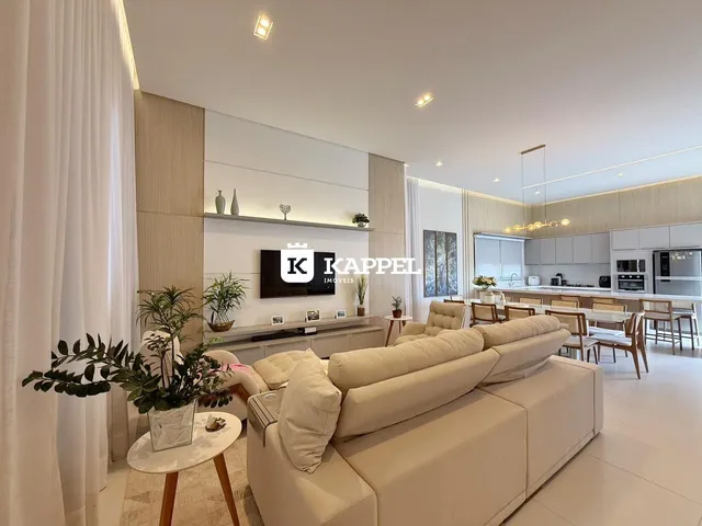 Sala de estar ampla com sofá bege e integração com a cozinha moderna.