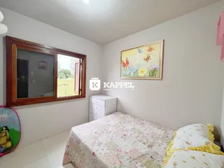 Quarto com cama coberta com estampa floral e janela de madeira.