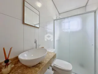 Banheiro com pia de apoio e box de vidro transparente.