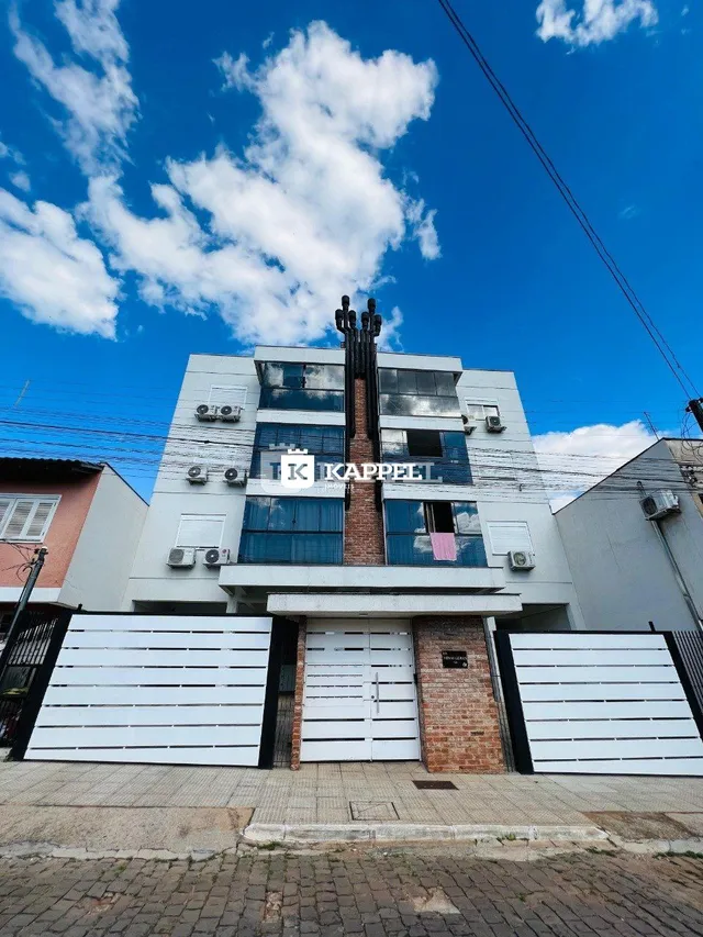 Fachada de um prédio residencial em Lajeado, Brasil, com janelas azuis e chaminé de tijolos aparentes.