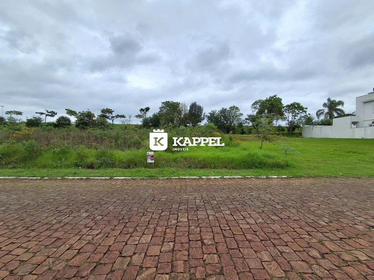 Foto da fachada de uma propriedade em Lajeado, Brasil, mostrando um gramado e uma área pavimentada.
