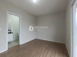 Ambiente interno de uma sala com piso de madeira clara.