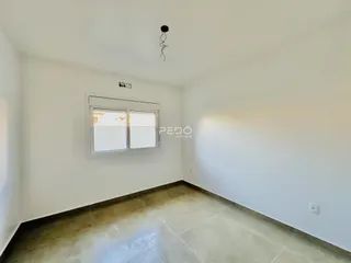 Vista interna de um cômodo com paredes brancas e piso de cerâmica.