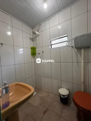 Foto de um banheiro com revestimento de azulejos brancos e uma pia.