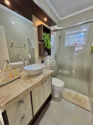 Foto do interior de um banheiro com bancada e box de vidro.