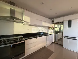Cozinha moderna com armários brancos e eletrodomésticos em aço inoxidável.