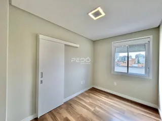 Ambiente interno de uma sala com piso de madeira e janela.