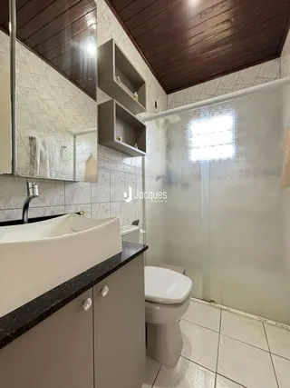 Interior de um banheiro com revestimento de azulejos e box de vidro.