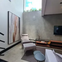 Ambiente interno com parede de textura cinza e tela escura na parede.