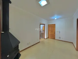 Interior de uma sala de estar com parede branca e piso claro.