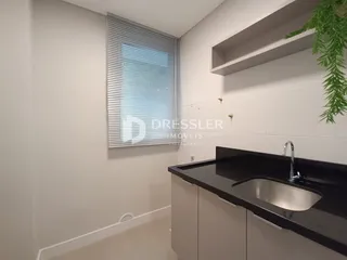 Vista de uma área de cozinha ou banheiro com bancada escura e armários brancos.