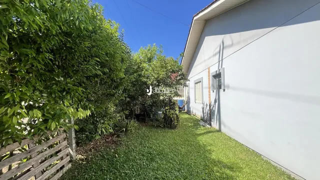 Vista da fachada de uma residência com vegetação densa ao redor.