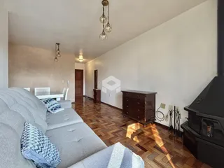 Sala de estar com piso de madeira e sofá cinza.