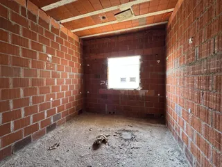 Interior de uma sala com paredes de tijolo aparente e piso de terra