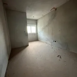 Foto de um corredor interno com paredes brancas e piso cru.