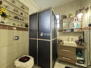 Foto de um banheiro com revestimento cerâmico e prateleiras de madeira.