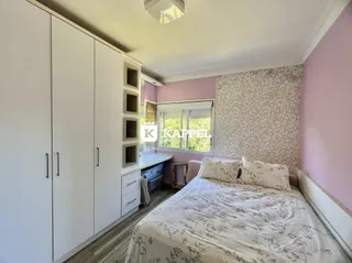 Quarto com cama e armários brancos em um ambiente claro.