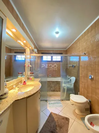 Foto de um banheiro com box de vidro e vaso sanitário em um imóvel.