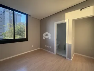 Interior de um ambiente com piso de madeira e porta de acesso a um banheiro.