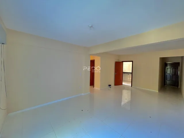 Uma sala de estar ampla com piso claro e paredes brancas.