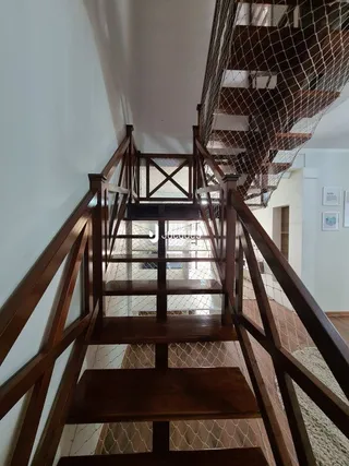 Vista de uma escadaria interna com corrimãos de madeira em uma residência.