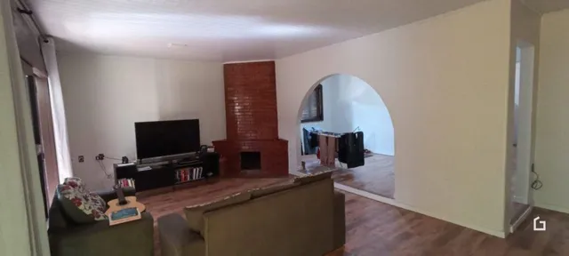 Uma sala com parede de tijolos aparentes e piso de madeira.
