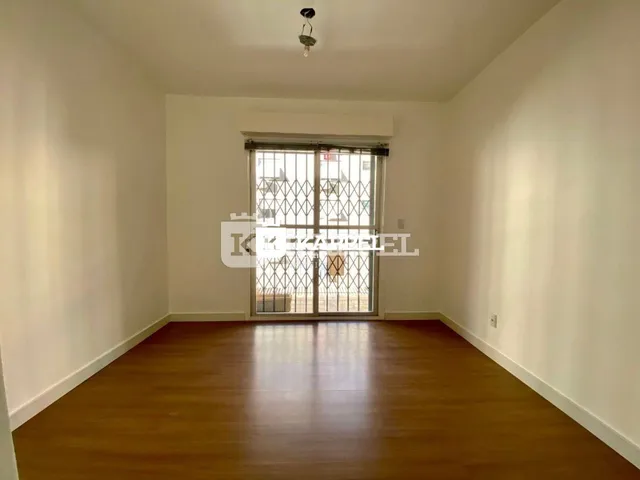 Sala de estar com piso de madeira e janela com grade de segurança.
