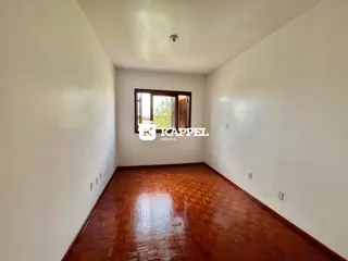Sala de estar com piso de madeira polida e paredes brancas.