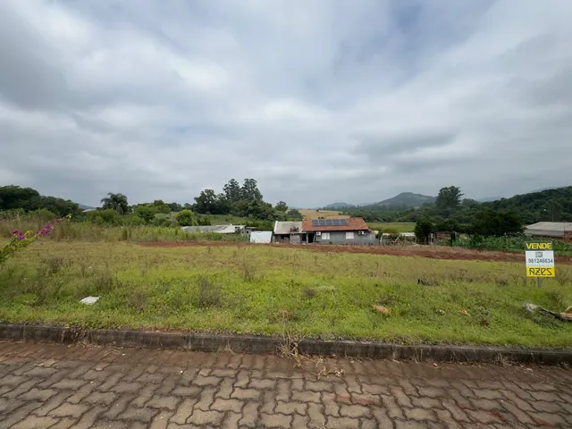 Vista panorâmica de uma área rural com vegetação e colinas ao fundo.