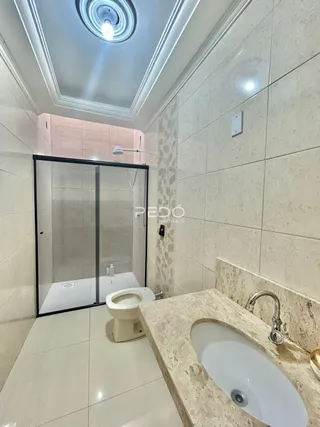 Foto de um banheiro com revestimento de cerâmica clara e louças brancas.