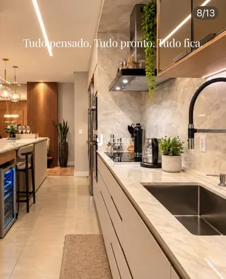 Cozinha moderna com armários brancos e bancadas de mármore claro.