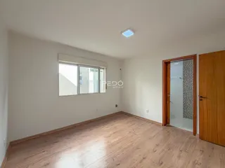 Foto de um ambiente interno com piso de madeira clara e parede branca.