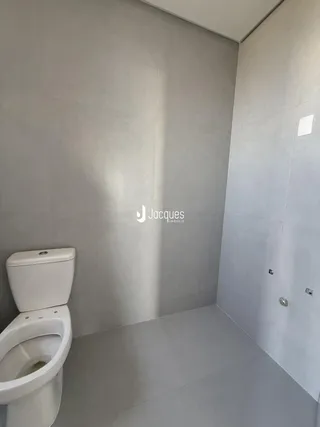 Foto do interior de um banheiro com paredes claras e piso liso.