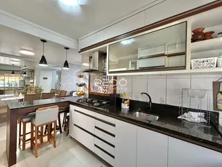 Vista da cozinha moderna com armários brancos e bancadas escuras.