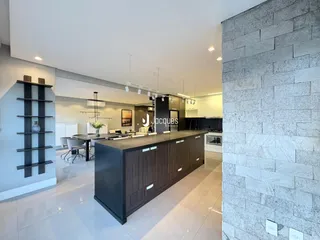 Vista da cozinha moderna com ilha escura e piso claro.