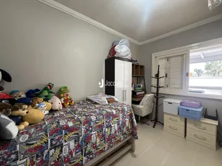Quarto com cama decorada e armário branco.