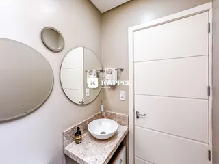 Banheiro com bancada de mármore e espelhos na parede.