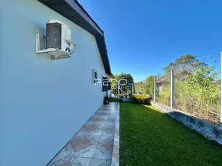 Fachada de uma residência com jardim e calçada de cerâmica.