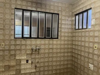 Parede de um banheiro com revestimento de azulejos claros e janelas.