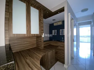 Ambiente interno de sala de estar e cozinha com piso de madeira.