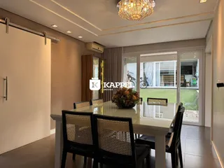 Sala de jantar com mesa de vidro e cadeiras de vime, com acesso a uma área externa.