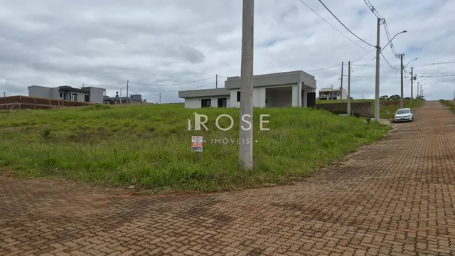 Vista externa de uma propriedade com terreno gramado e estrada de paralelepípedos.