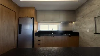 Foto da cozinha com armários de madeira e bancada escura.