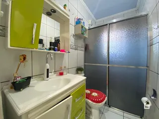 Foto de um banheiro com bancada branca e divisória de vidro.
