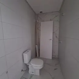 Foto de um banheiro com revestimento branco e vaso sanitário.